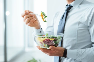 person in formal attire eating a salad standing up